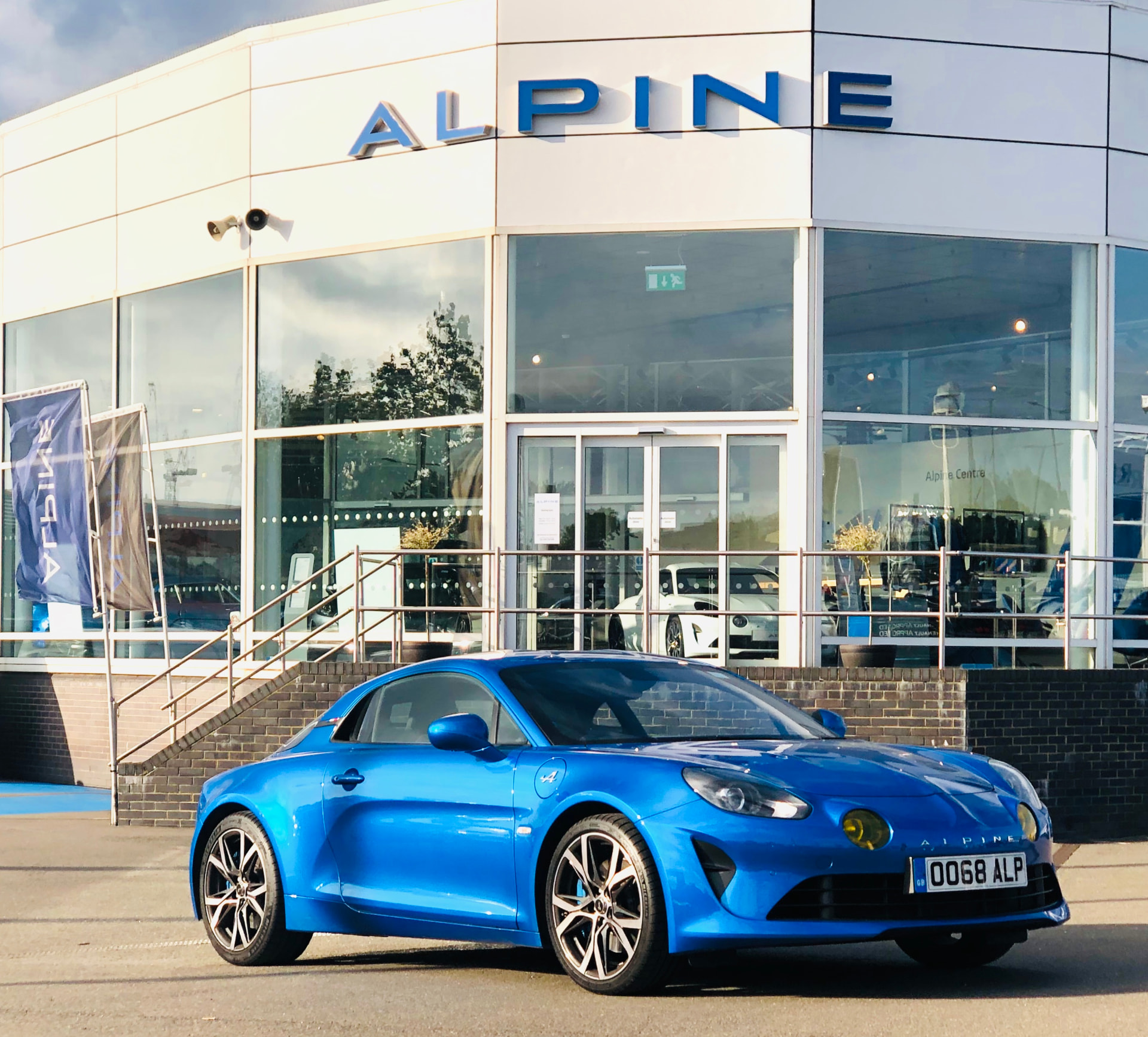 Alpine sports car parked outside a dealership showroom